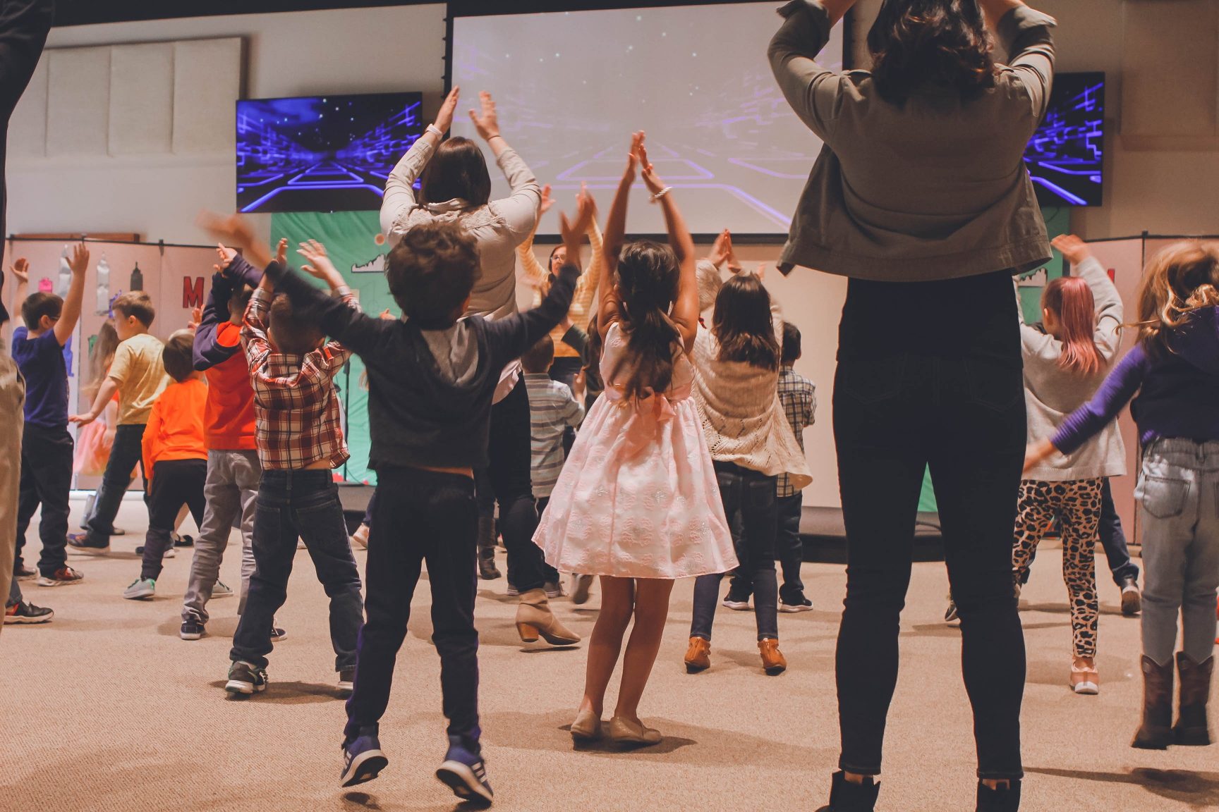 Children with their hands in the air taking part in a group activity.